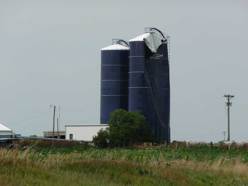 two blue silos, one with a crease in it